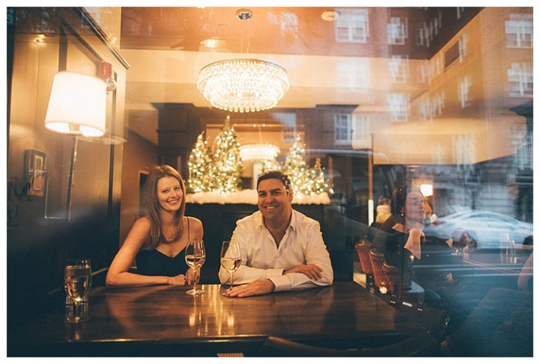 A man and woman enjoying drinks at a bar with warm lighting.