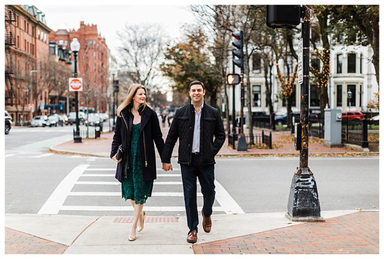 A couple walking hand-in-hand across a city street.