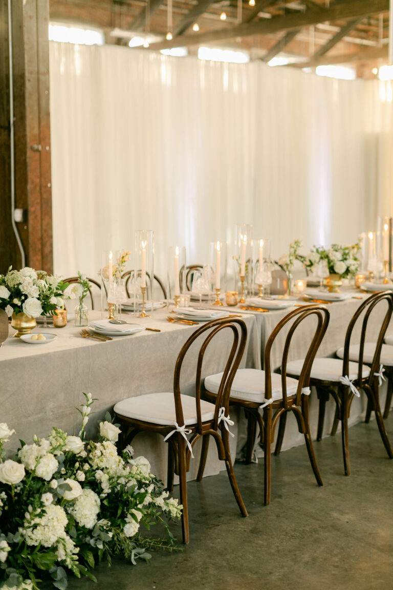 Elegant dining table setup with floral decorations and wooden chairs.